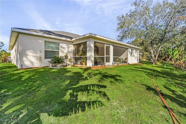 back of property with a yard and a sunroom