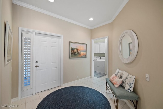 foyer entrance with ornamental molding, washing machine and dryer, and light tile patterned floors