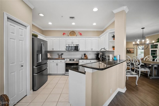 kitchen with crown molding, hanging light fixtures, kitchen peninsula, stainless steel appliances, and white cabinets