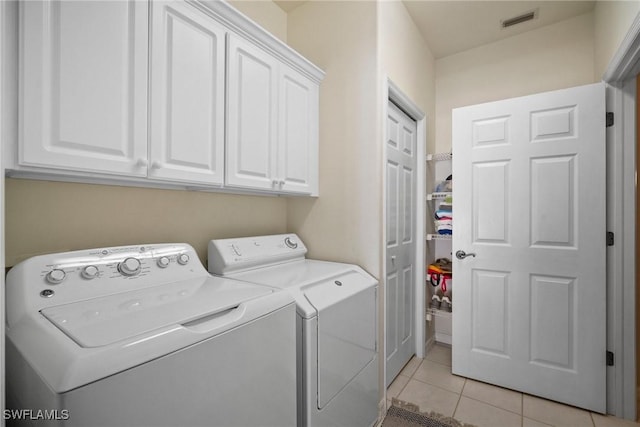 washroom featuring light tile patterned floors, cabinets, and washing machine and clothes dryer