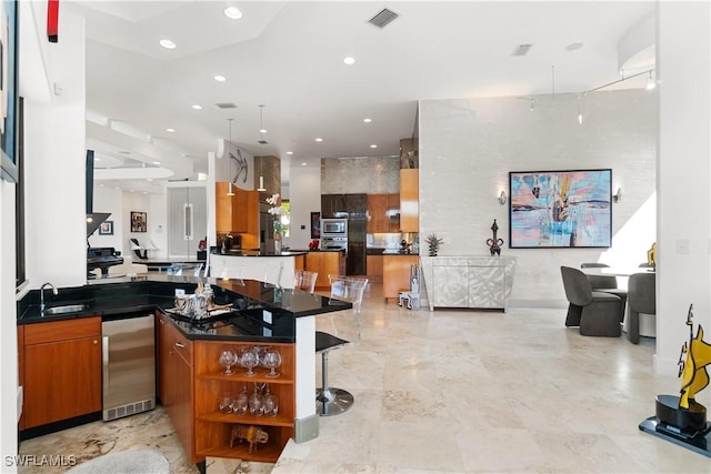 kitchen featuring a breakfast bar, pendant lighting, stainless steel microwave, sink, and kitchen peninsula