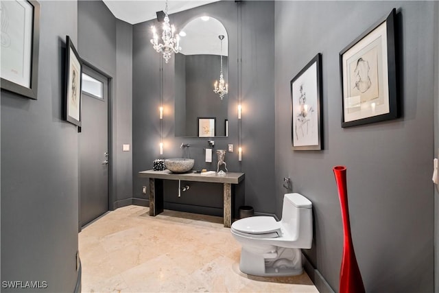 bathroom with an inviting chandelier, vanity, and toilet