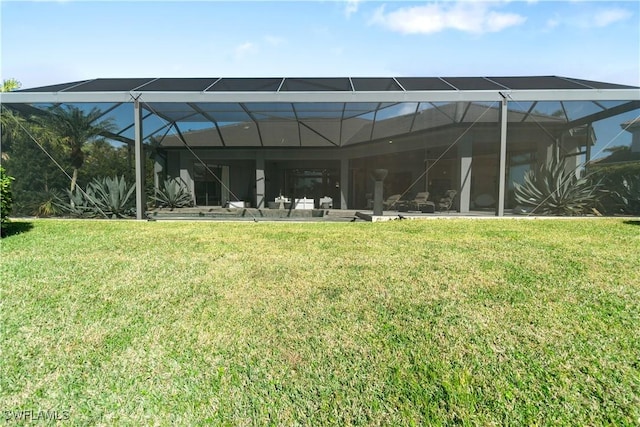 rear view of property featuring a yard and glass enclosure