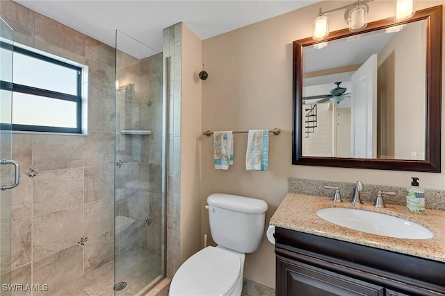 bathroom with vanity, toilet, ceiling fan, and a shower with shower door