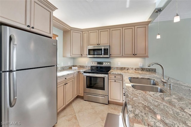 kitchen featuring light stone counters, sink, pendant lighting, and appliances with stainless steel finishes