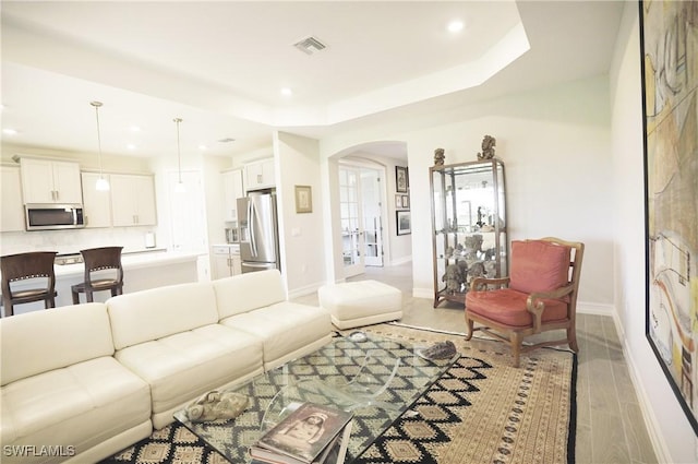 living room featuring light wood-type flooring and a tray ceiling