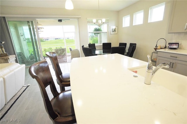 dining room with ceiling fan with notable chandelier and light hardwood / wood-style flooring