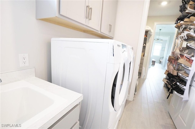 laundry area featuring washer and dryer, sink, light hardwood / wood-style flooring, and cabinets