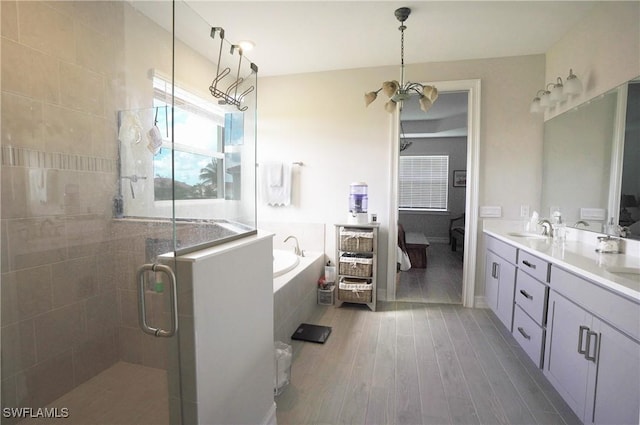 bathroom featuring hardwood / wood-style flooring, vanity, separate shower and tub, and a chandelier