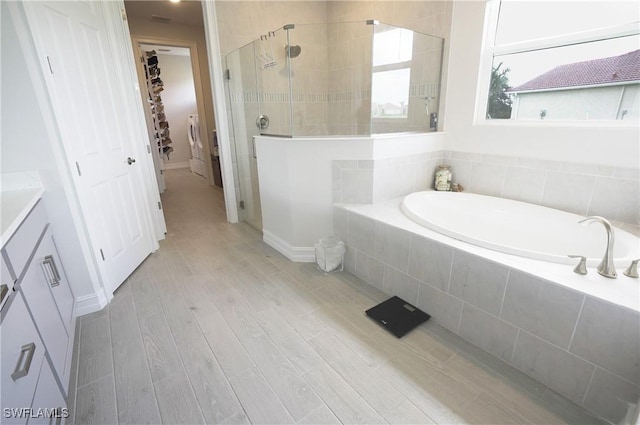 bathroom with hardwood / wood-style flooring, vanity, and separate shower and tub