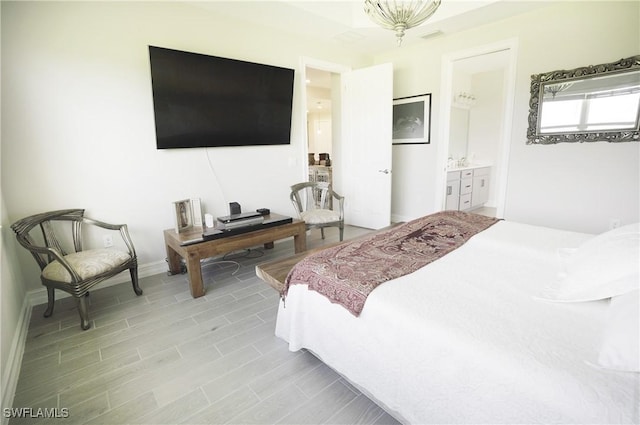 bedroom featuring light wood-type flooring and ensuite bath