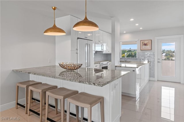 kitchen featuring white cabinetry, decorative light fixtures, white appliances, and stone countertops