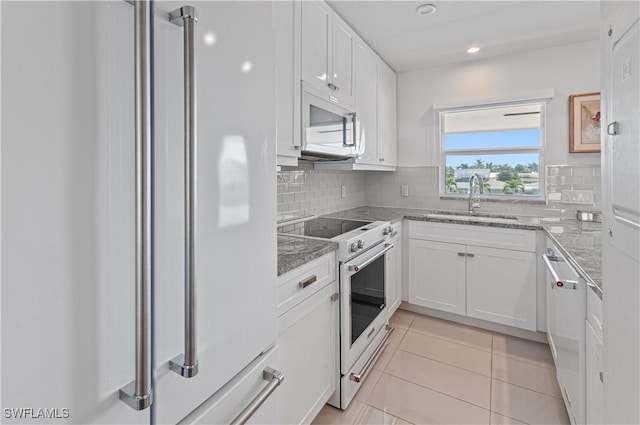 kitchen featuring premium appliances, decorative backsplash, sink, and white cabinets