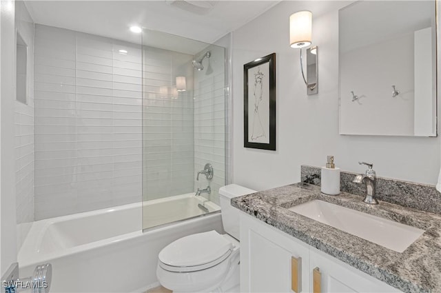 full bathroom featuring vanity, tiled shower / bath combo, and toilet