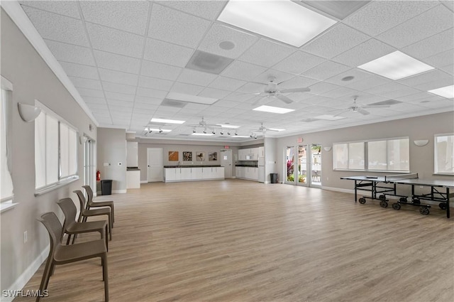 interior space with ceiling fan, a drop ceiling, and light wood-type flooring