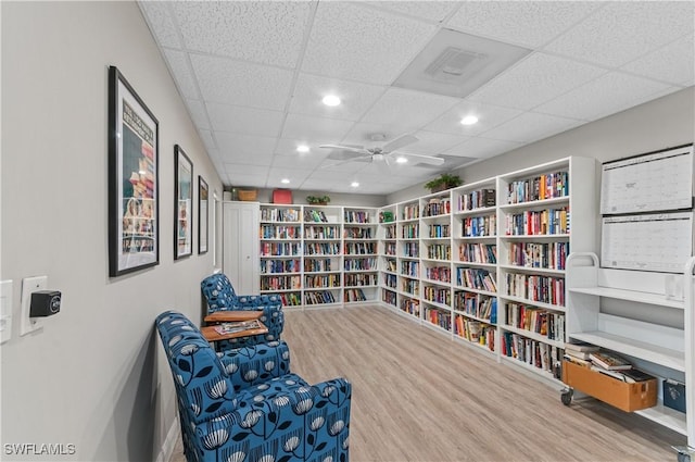 living area featuring a paneled ceiling, hardwood / wood-style floors, and ceiling fan