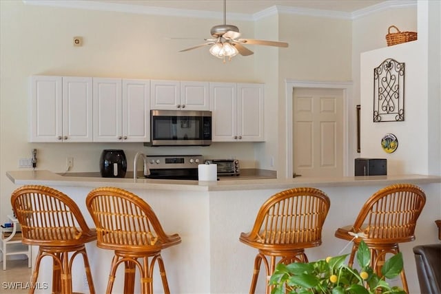 kitchen featuring crown molding, appliances with stainless steel finishes, kitchen peninsula, and white cabinets