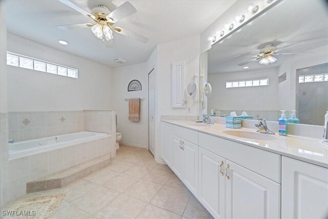 bathroom featuring tiled bath, tile patterned flooring, vanity, ceiling fan, and toilet