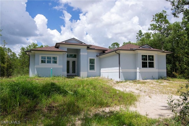 view of front facade with stucco siding and french doors