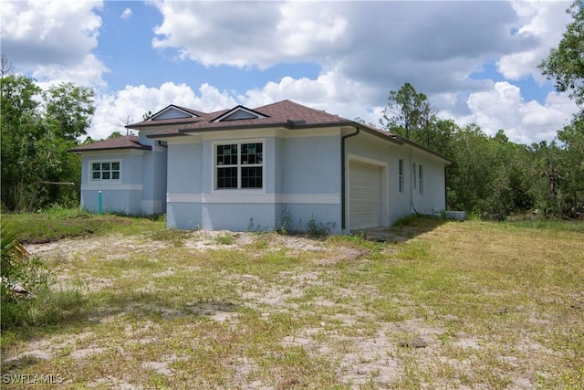 view of side of home with a garage, driveway, a shingled roof, and stucco siding