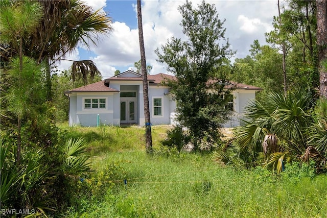 rear view of property with stucco siding and french doors