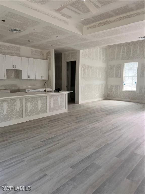 kitchen with a sink, visible vents, white cabinetry, open floor plan, and light wood-type flooring