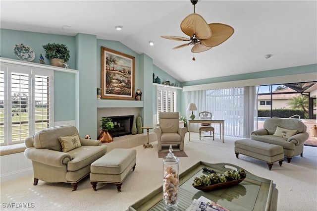 carpeted living room featuring vaulted ceiling, a tile fireplace, and ceiling fan