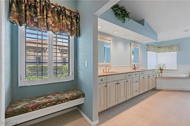 bathroom featuring lofted ceiling, vanity, a washtub, and a healthy amount of sunlight