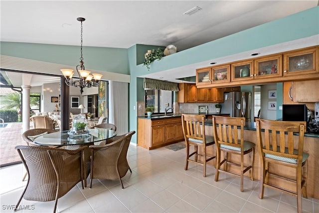 tiled dining area featuring an inviting chandelier, sink, and vaulted ceiling