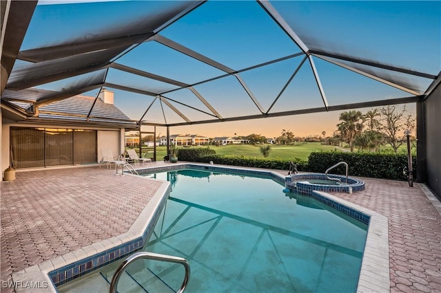 pool at dusk with an in ground hot tub, a patio, and glass enclosure