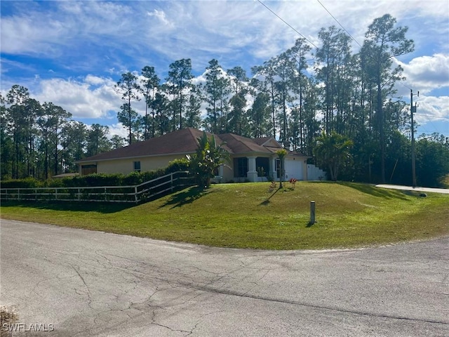 ranch-style home featuring a front lawn, a garage, and a fenced front yard