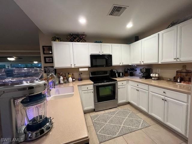 822 Johns Ave, Lehigh Acres, FL 33972 - kitchen featuring stainless steel range with electric stovetop, black microwave, light tile patterned floors, white cabinets, and light countertops