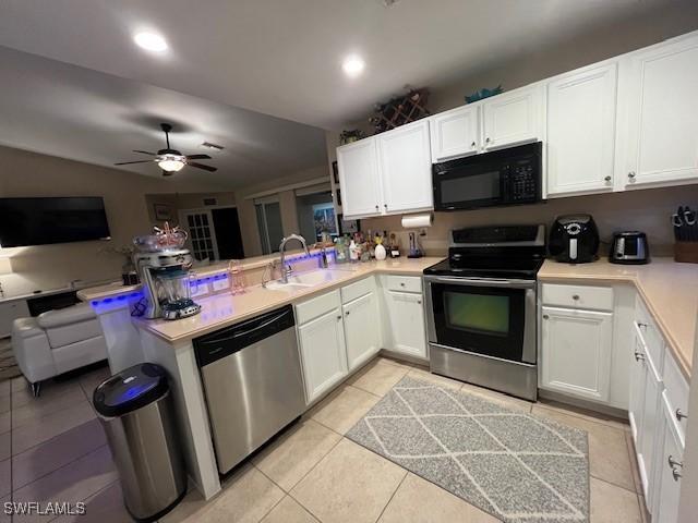 kitchen with sink, light tile patterned floors, kitchen peninsula, stainless steel appliances, and white cabinets