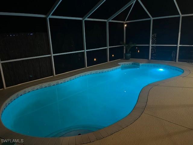 pool with glass enclosure and a patio