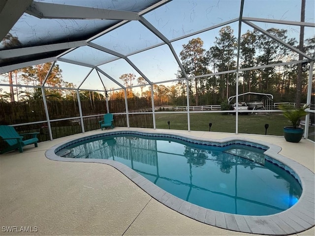 pool at dusk featuring a patio, a yard, and glass enclosure