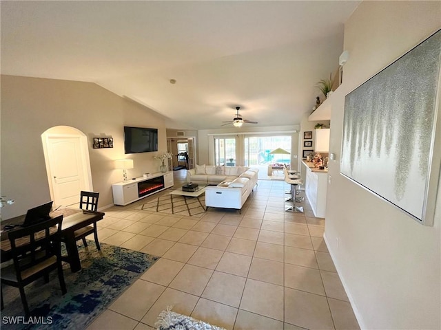 822 Johns Ave, Lehigh Acres, FL 33972 - living room with a glass covered fireplace, light tile patterned floors, vaulted ceiling, ceiling fan, and arched walkways