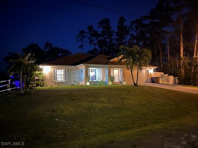 822 Johns Ave, Lehigh Acres, FL 33972 - ranch-style home with concrete driveway, a lawn, and an attached garage