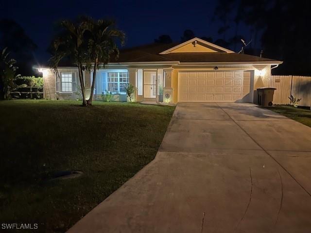 ranch-style home featuring a lawn, an attached garage, concrete driveway, and fence