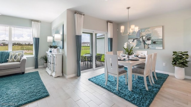 dining area featuring light wood-type flooring, an inviting chandelier, and baseboards