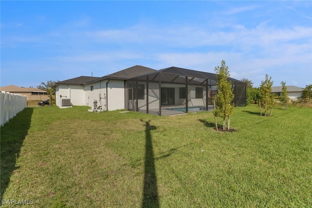 rear view of house featuring a yard, glass enclosure, and central air condition unit