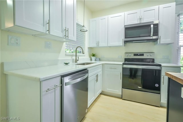 kitchen featuring white cabinetry, sink, light hardwood / wood-style floors, and appliances with stainless steel finishes