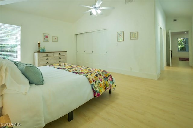 bedroom featuring vaulted ceiling, ceiling fan, light hardwood / wood-style floors, and multiple windows