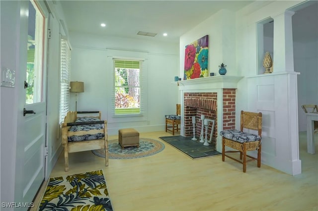 living area with hardwood / wood-style flooring and a brick fireplace