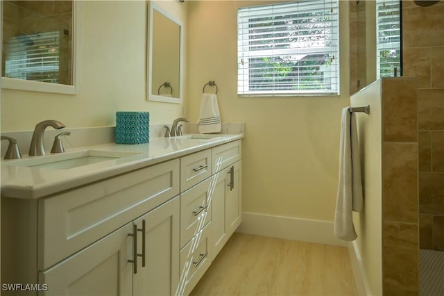 bathroom with hardwood / wood-style flooring, vanity, and a tile shower