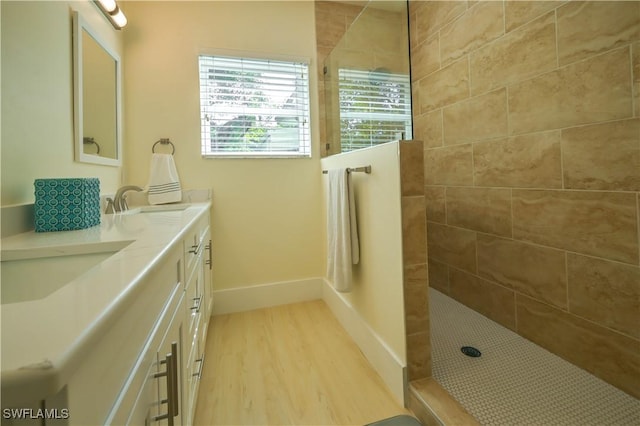 bathroom featuring hardwood / wood-style flooring, vanity, and a tile shower