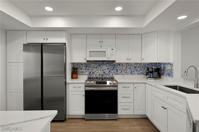 kitchen featuring sink, light hardwood / wood-style flooring, white cabinets, and appliances with stainless steel finishes