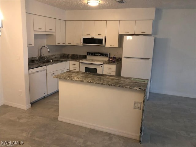 kitchen featuring sink, white appliances, white cabinetry, a textured ceiling, and dark stone counters