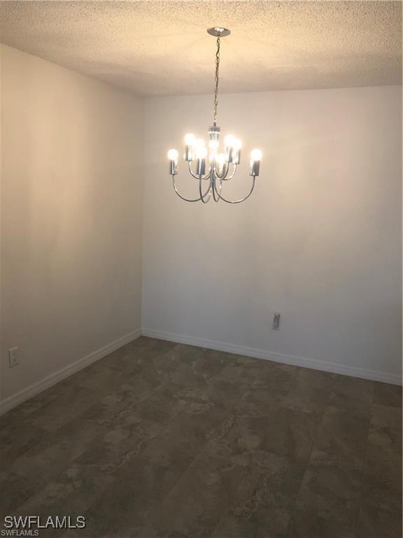 empty room with an inviting chandelier and a textured ceiling