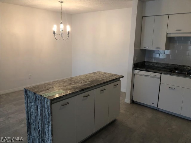 kitchen with white cabinetry, hanging light fixtures, white dishwasher, dark stone counters, and decorative backsplash