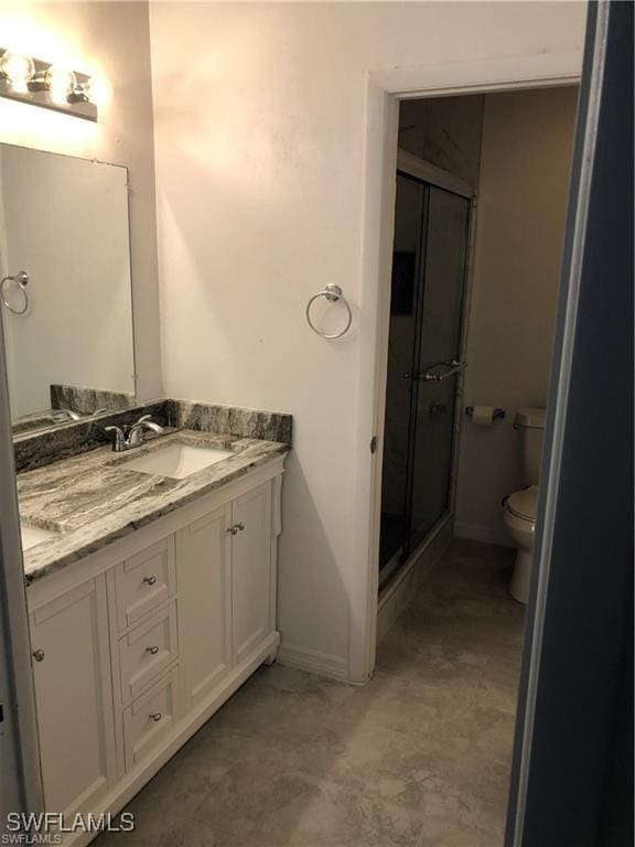 bathroom featuring vanity, an enclosed shower, and toilet